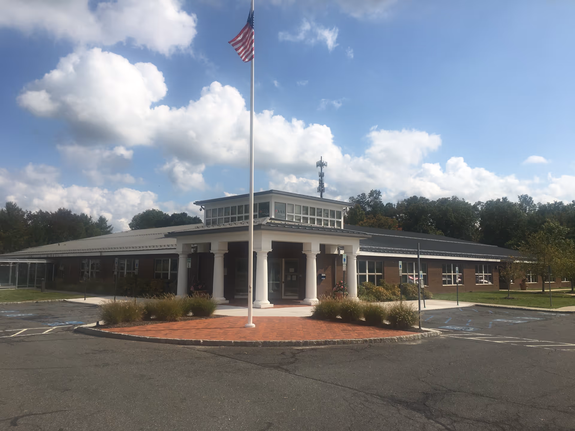 Exterior view of Atlantic Private Care Services building with flagpole, entrance portico, and parking lot.
