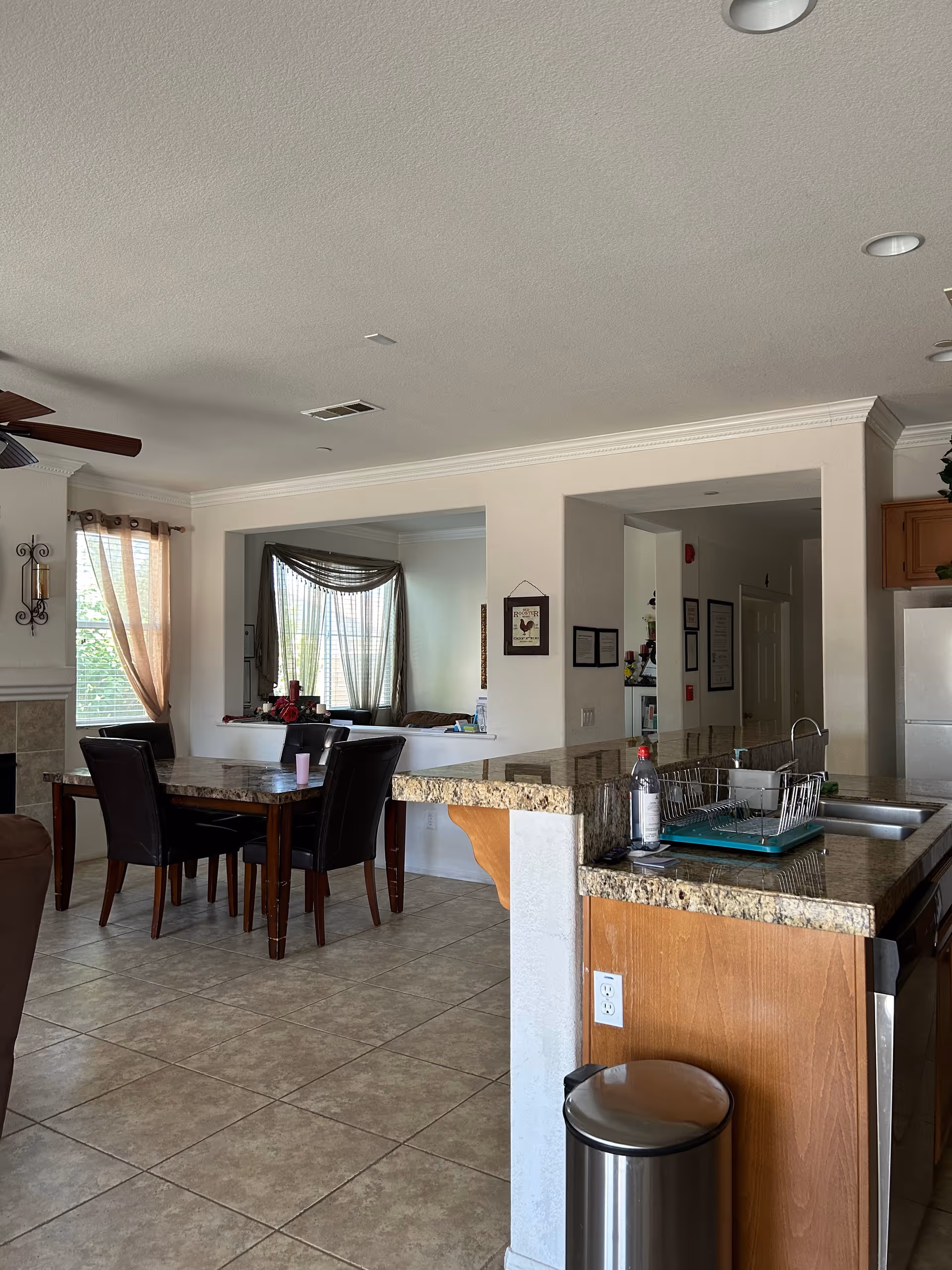 Open-concept dining area in a senior living facility with granite island and windows.