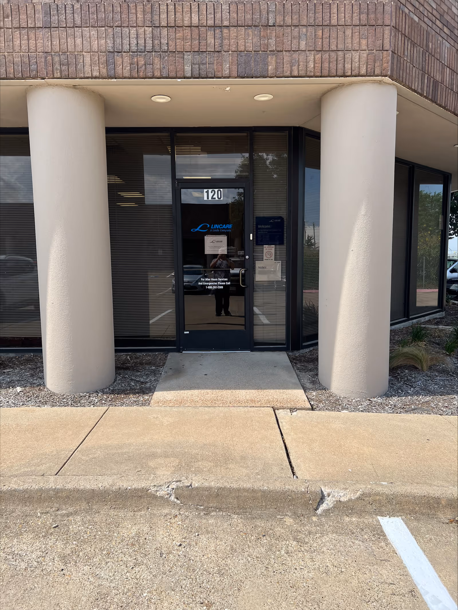 Exterior view of LINCARE INC entrance with glass door and large columns.