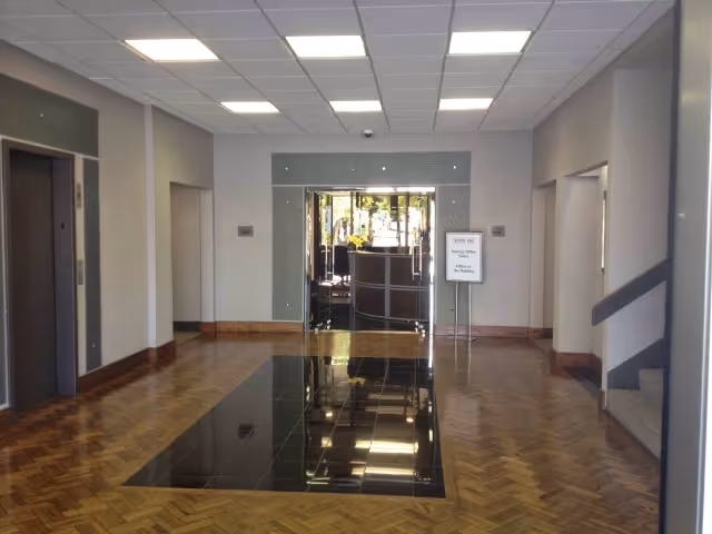 Long interior hallway in a senior living facility with reflective black floor insert and ceiling lights.