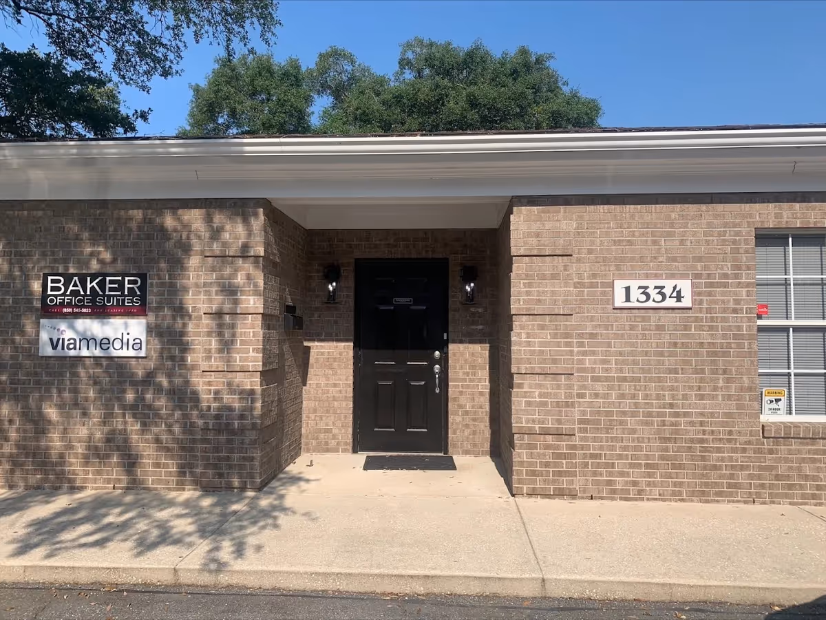 Brick building exterior with a black front door and entrance signs