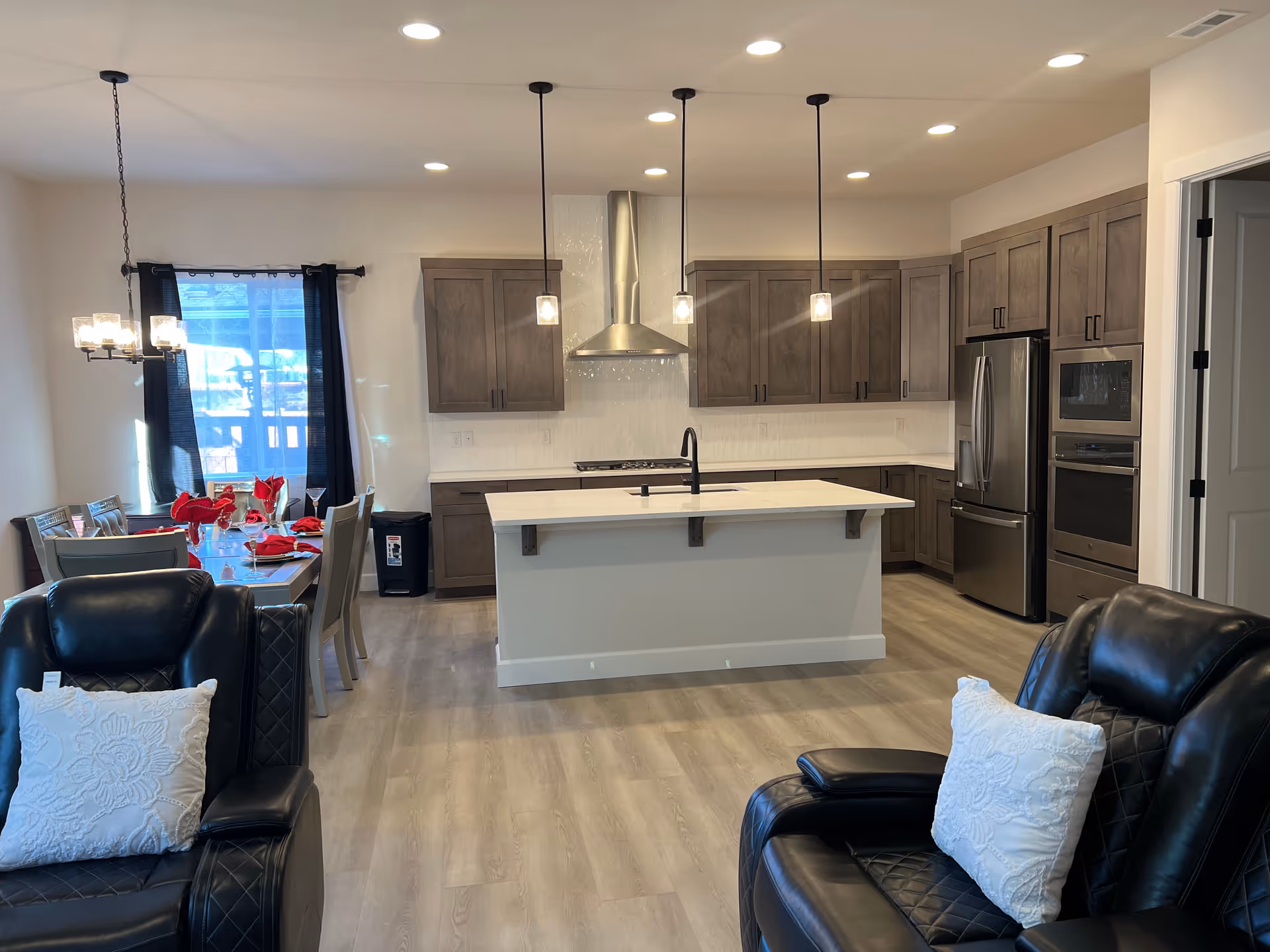 Open-concept living area with a modern kitchen island, dining table, and leather seating.