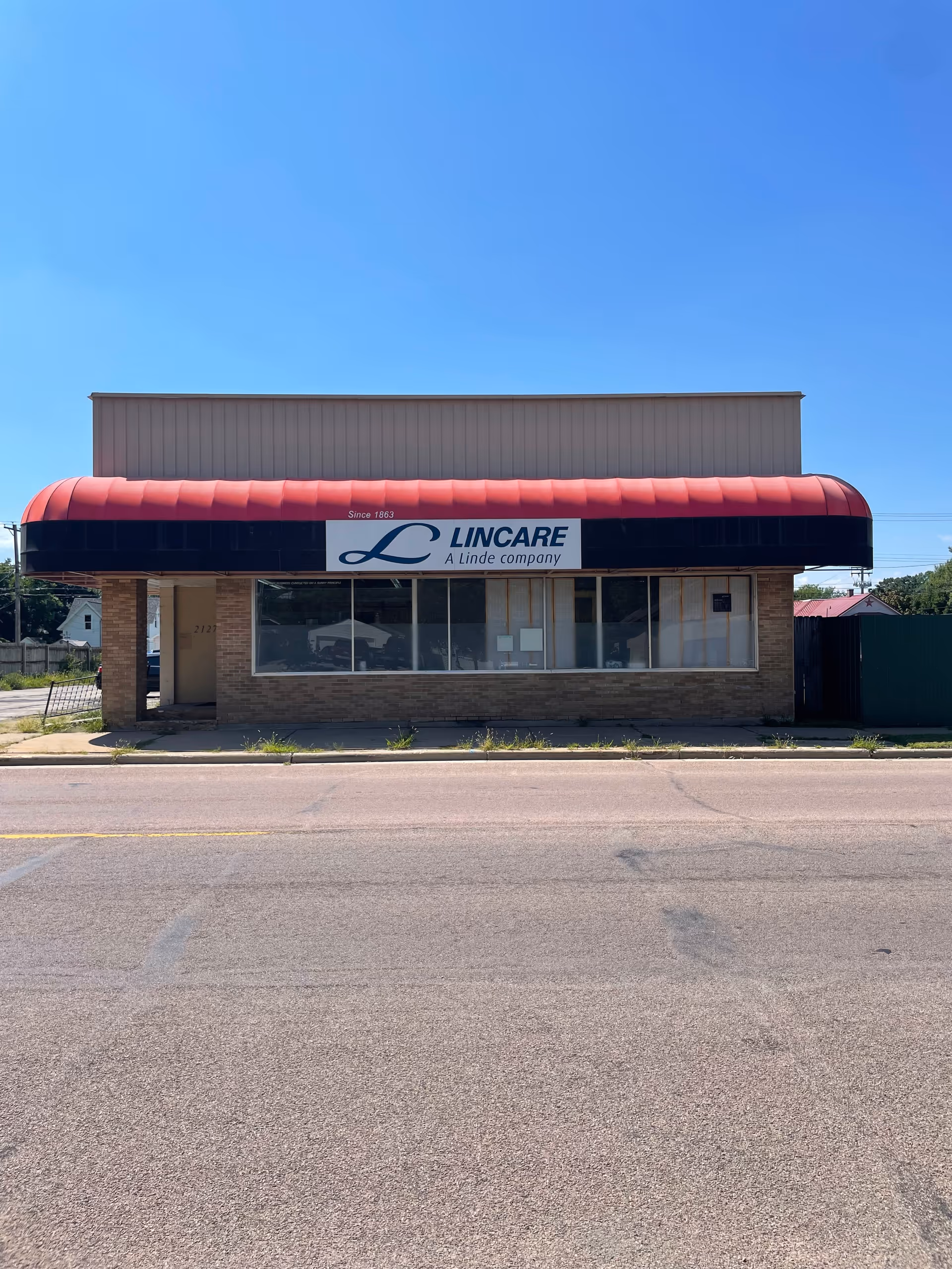 Front of a single-story building with a red awning and LINCARE sign.
