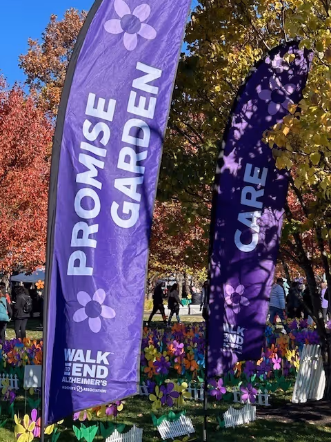 Purple Promise Garden banners with flowers decorate an outdoor event.