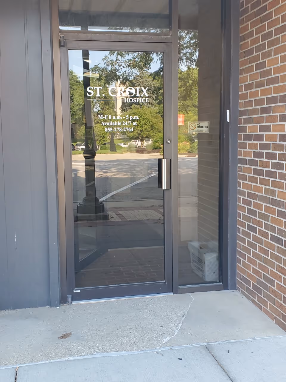 Glass door entrance labeled St. Croix Hospice with brick exterior and sidewalk.