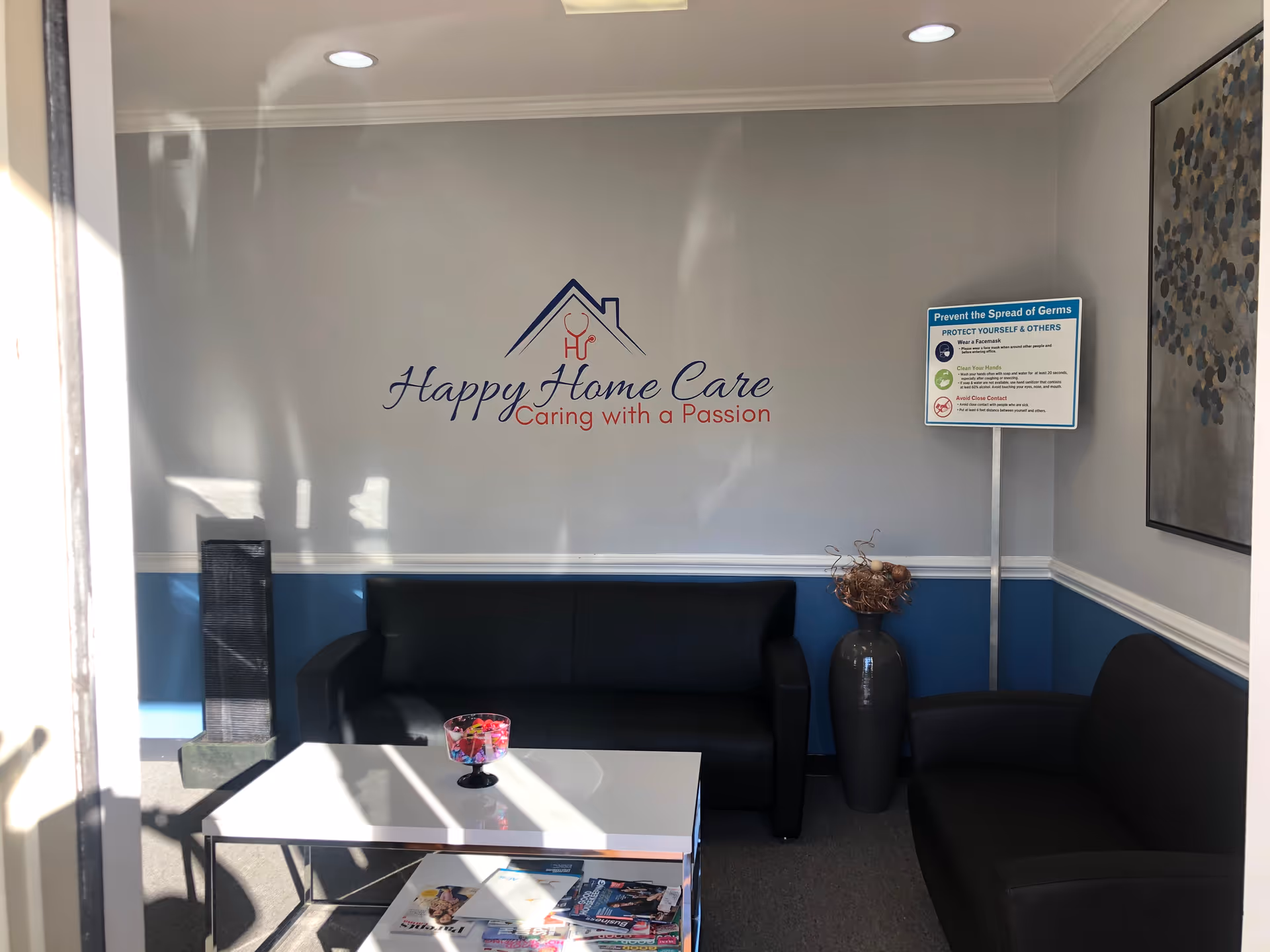 Lobby seating area with sofas, coffee table, and a sign for Happy Home Care.