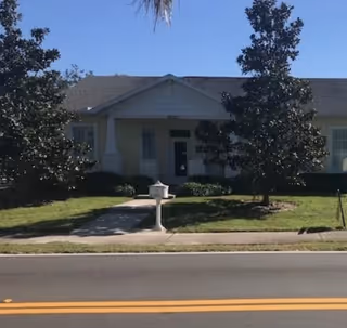 Front view of a single-story senior living building with lawn and mailbox