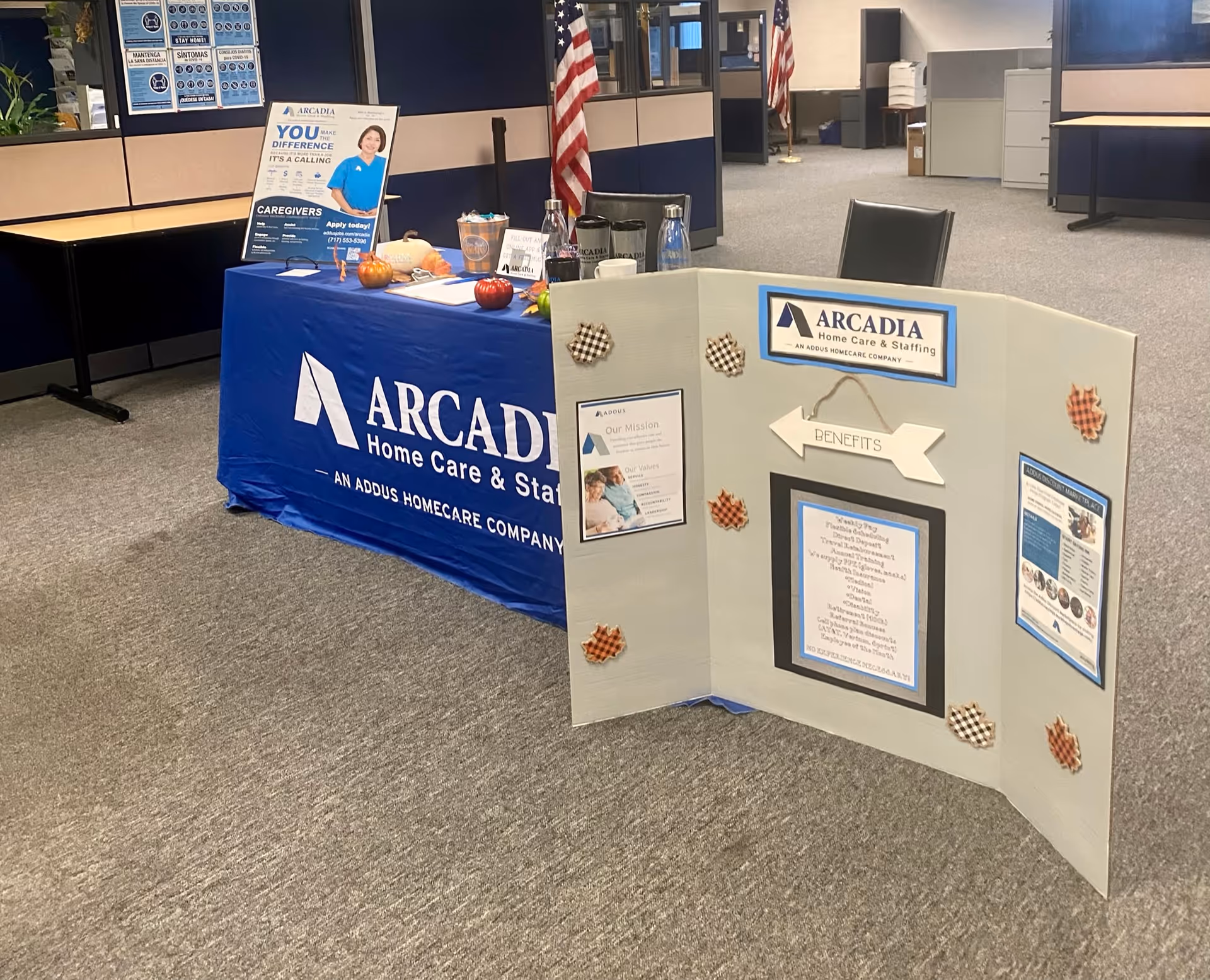 Indoor Arcadia Home Care Staffing booth with blue table cover and display panels.