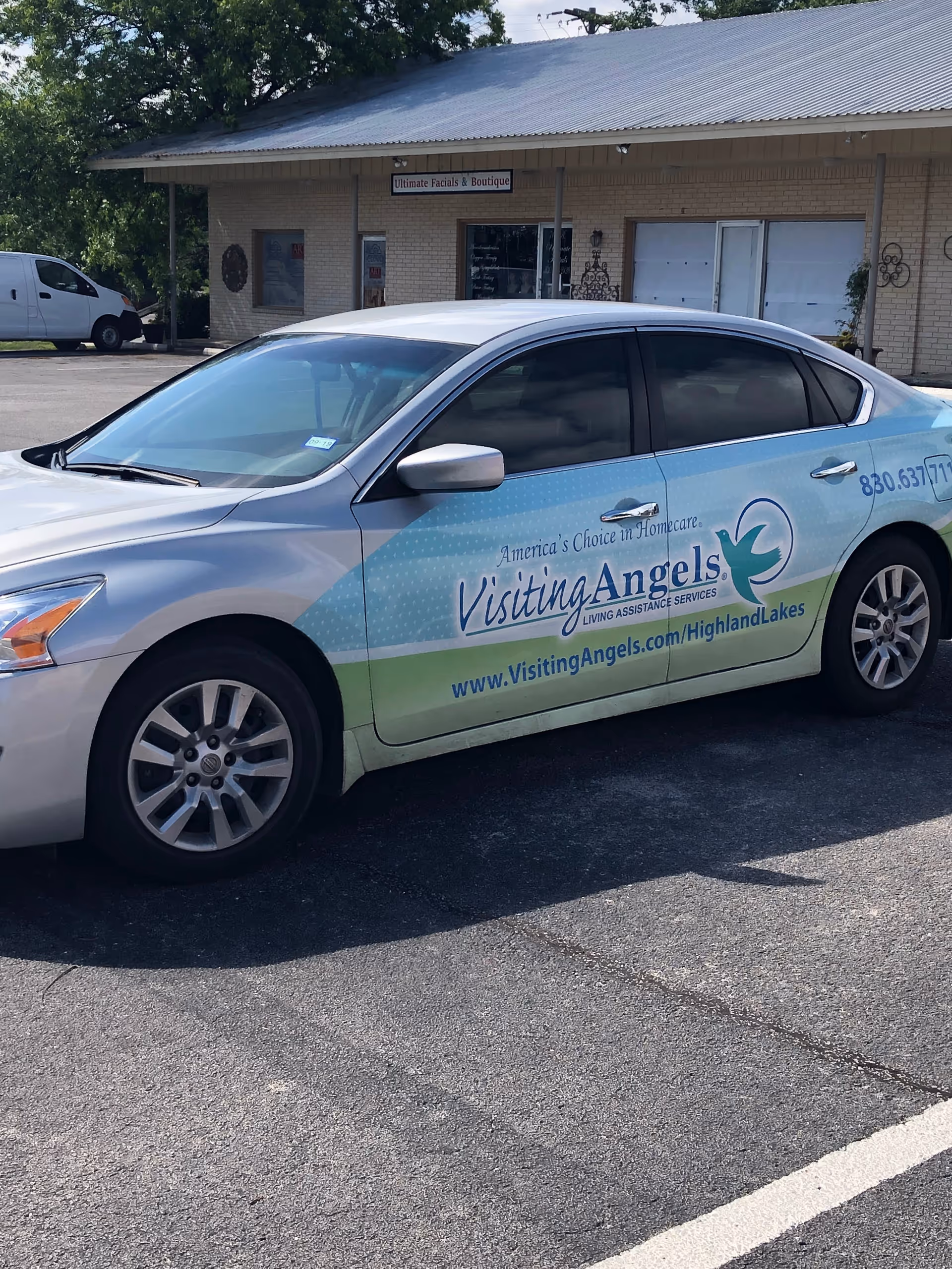 A Visiting Angels van is parked in front of a small brick building.