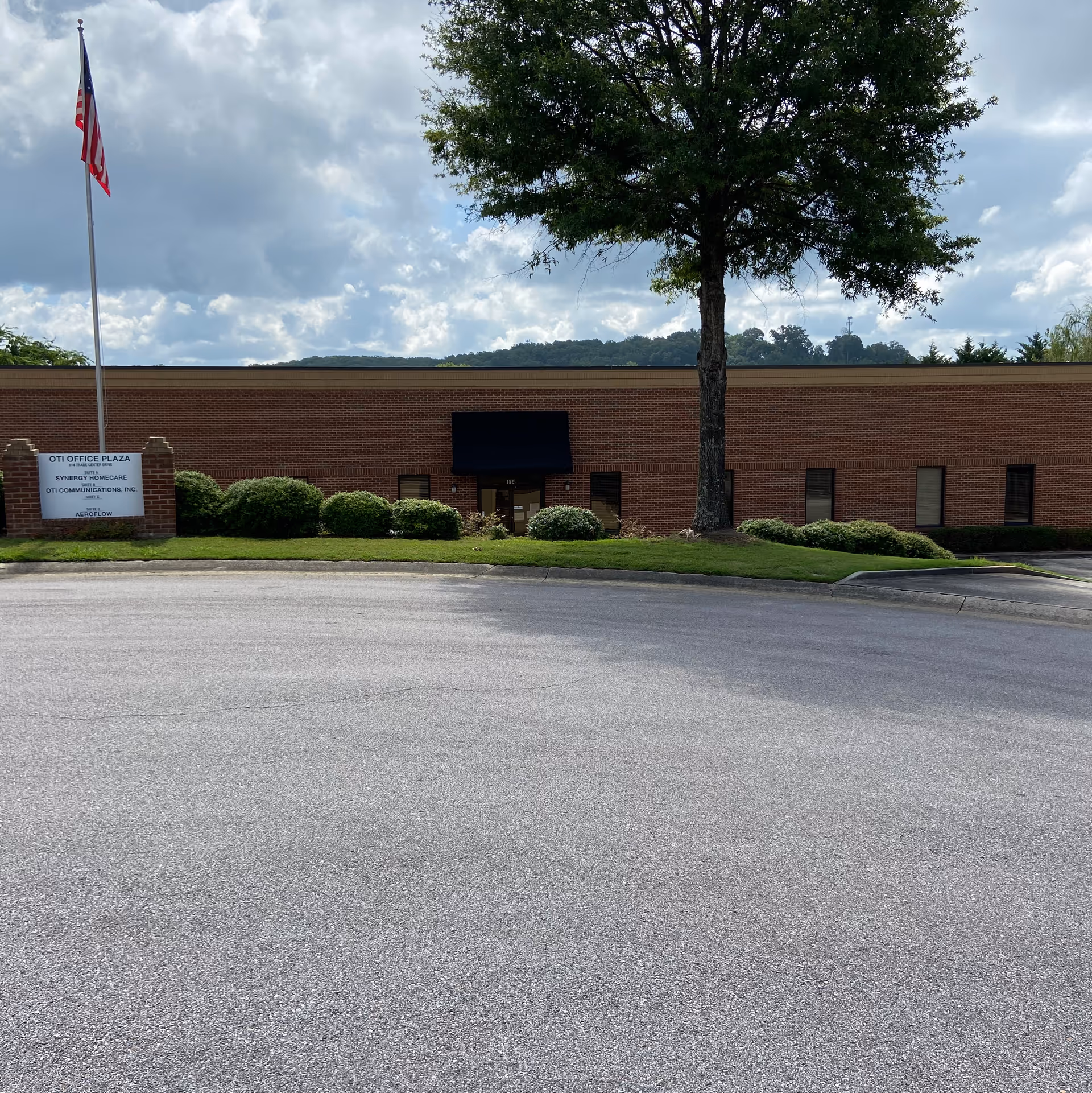 Exterior view of a brick senior care building with landscaping and a flagpole.