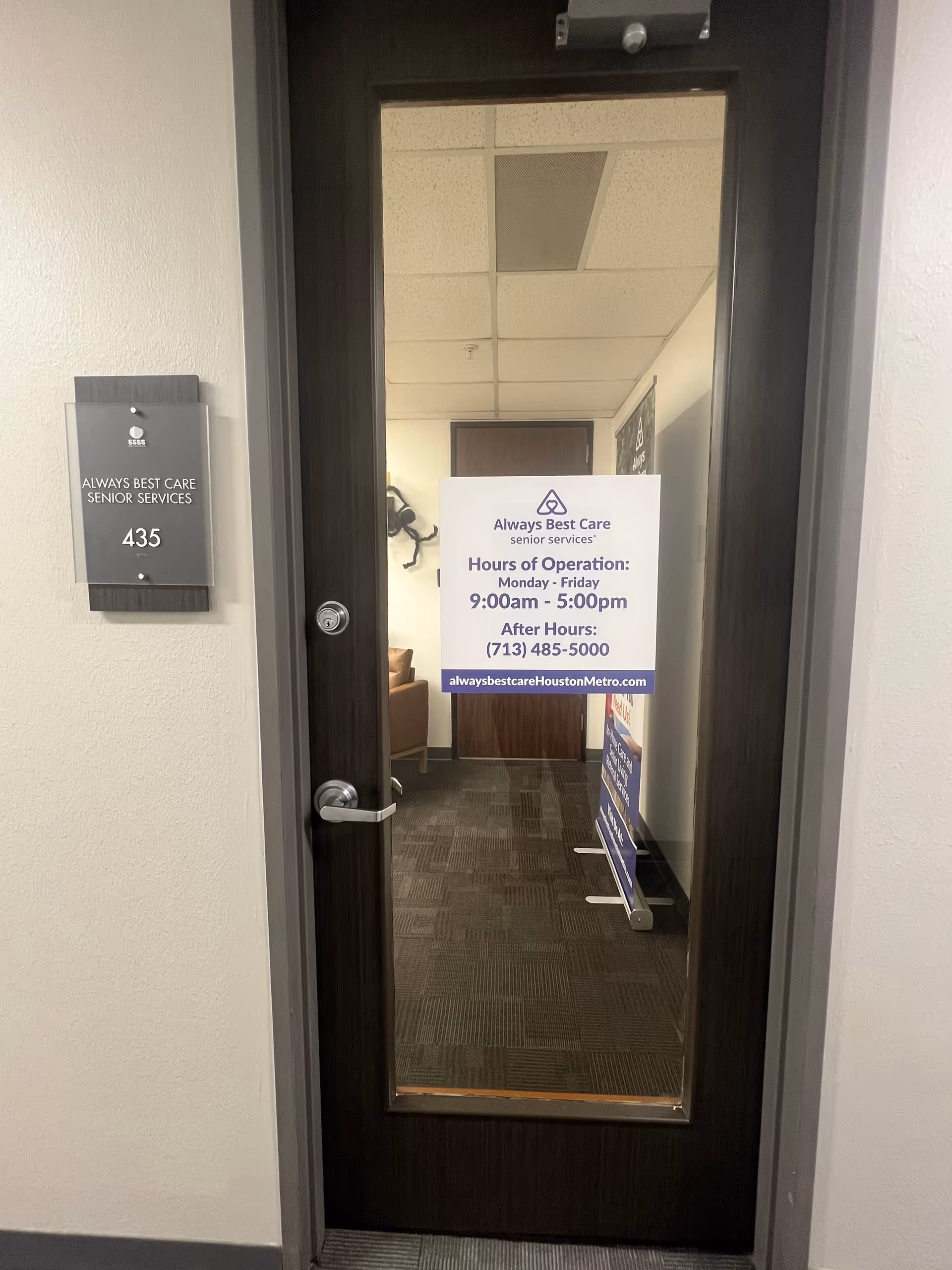 Glass door leads to interior hallway with hours of operation sign.