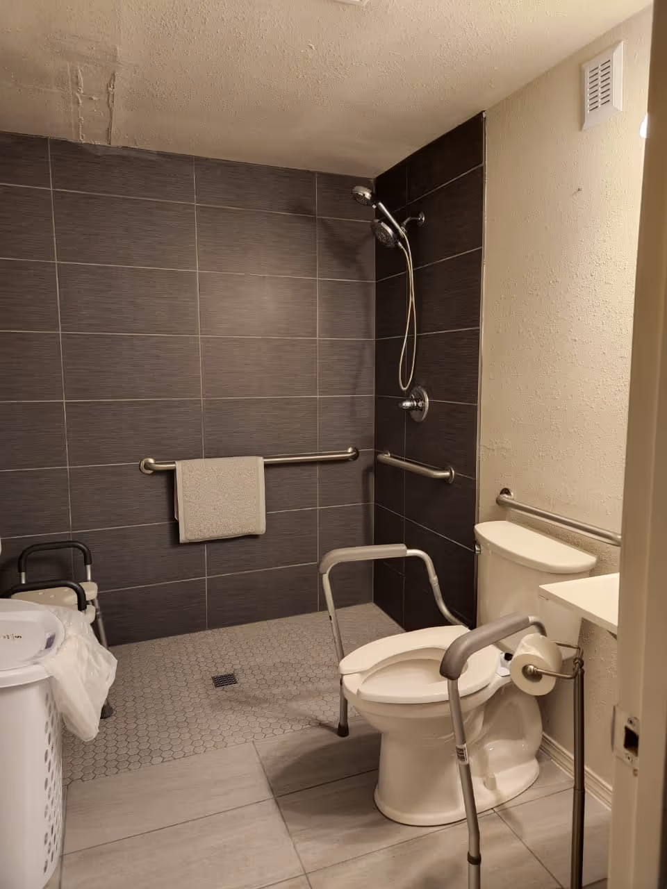 Accessible bathroom with shower, toilet, and safety grab bars in a senior facility.