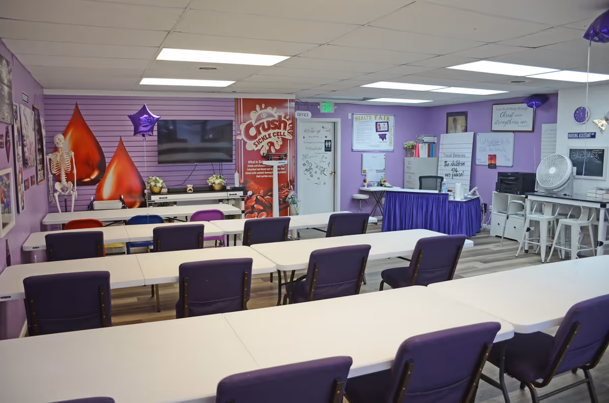 Purple-walled senior living facility dining room with long white tables and purple chairs.