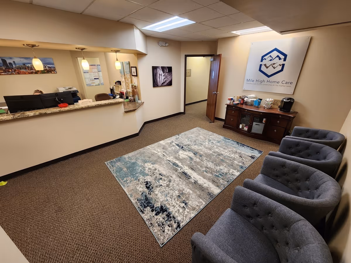 Reception area with curved counter, gray chairs, rug, and Mile High Home Care sign.