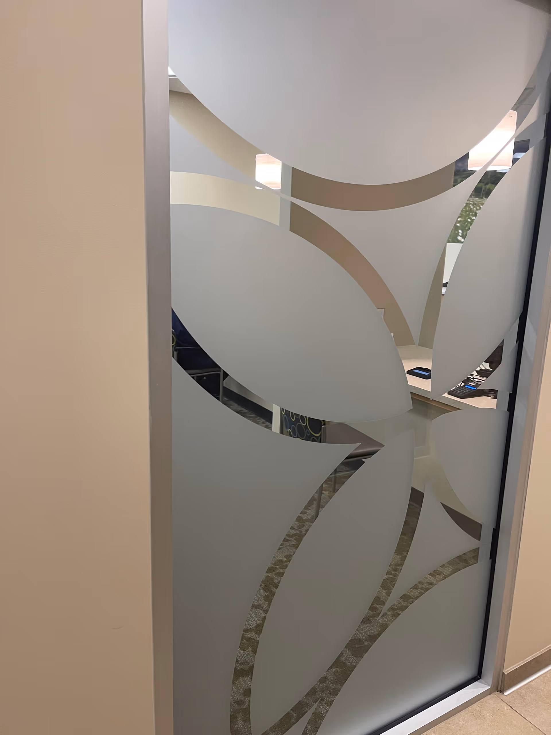 Frosted glass door with abstract leaf patterns in an interior hallway.