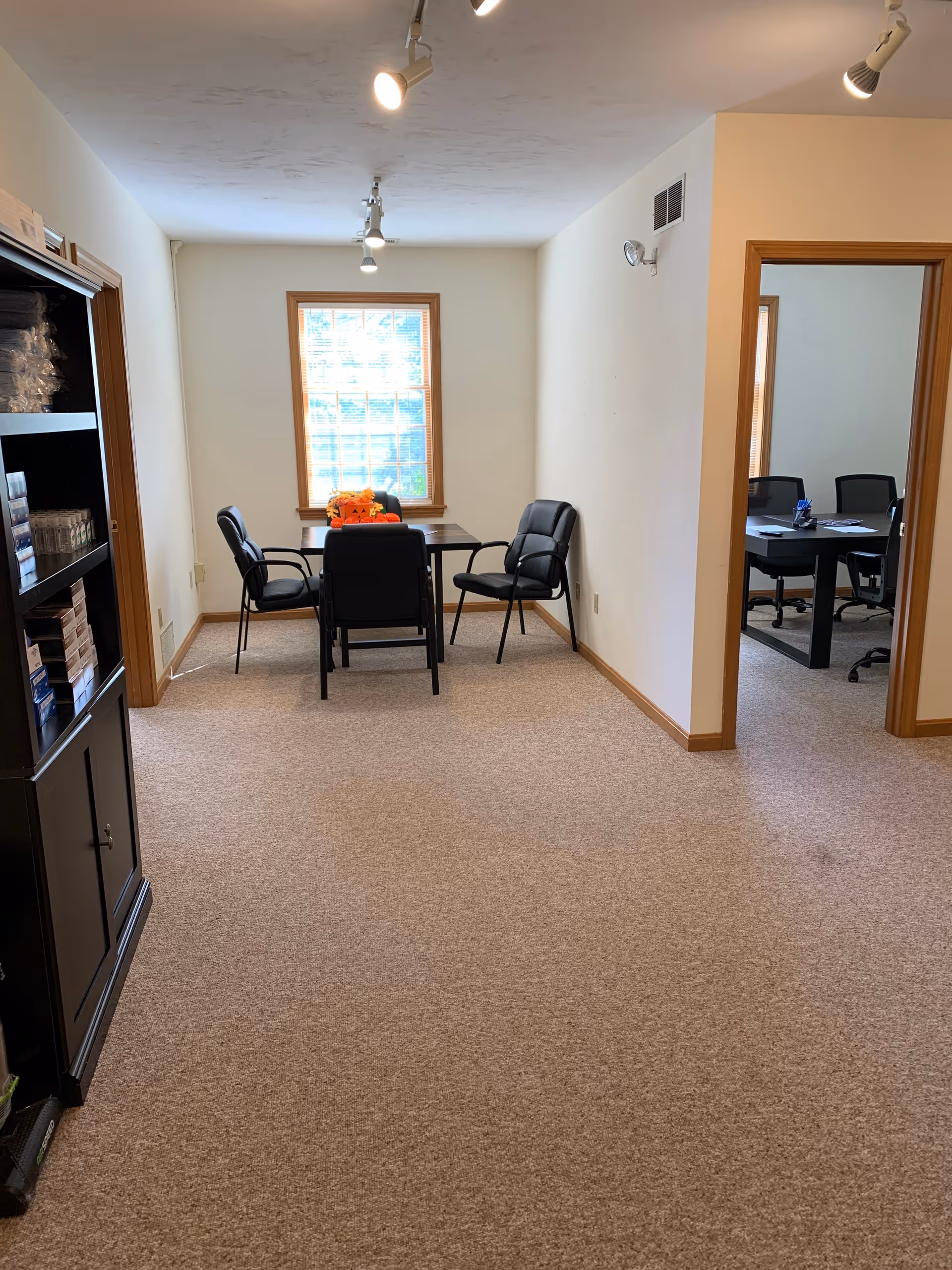 Small interior conference room with table, chairs, cabinet, and window in a senior care facility.