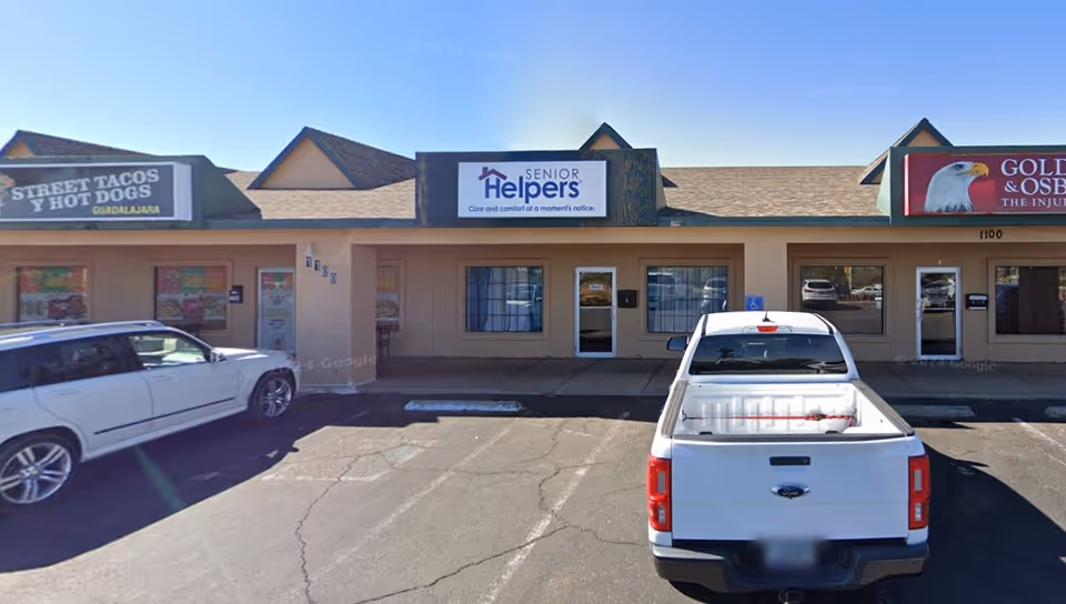 Front exterior of a strip mall with Senior Helpers storefront and parked cars.