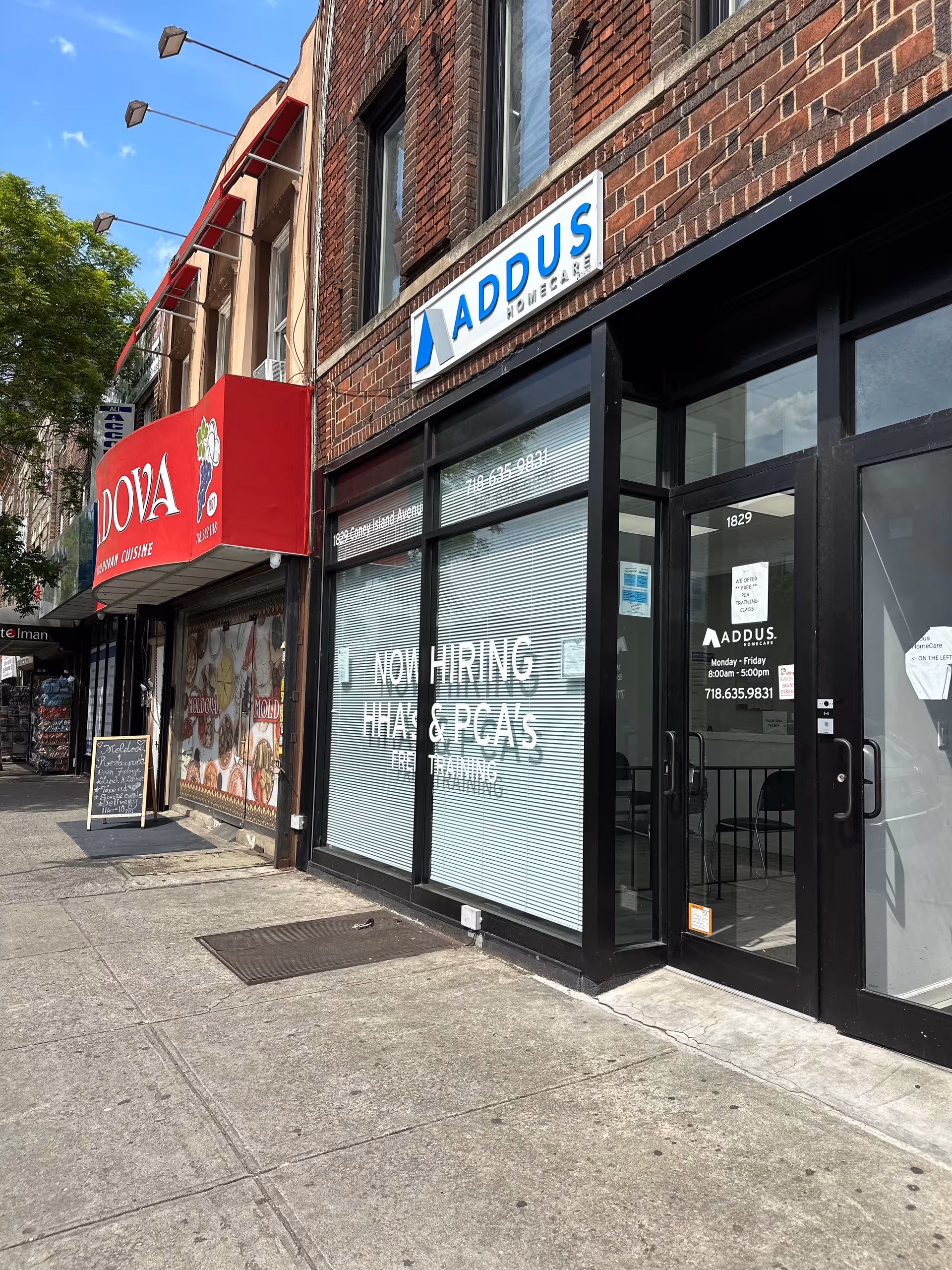 Street-front view of Addus HomeCare storefront beside a restaurant on a sunny day.