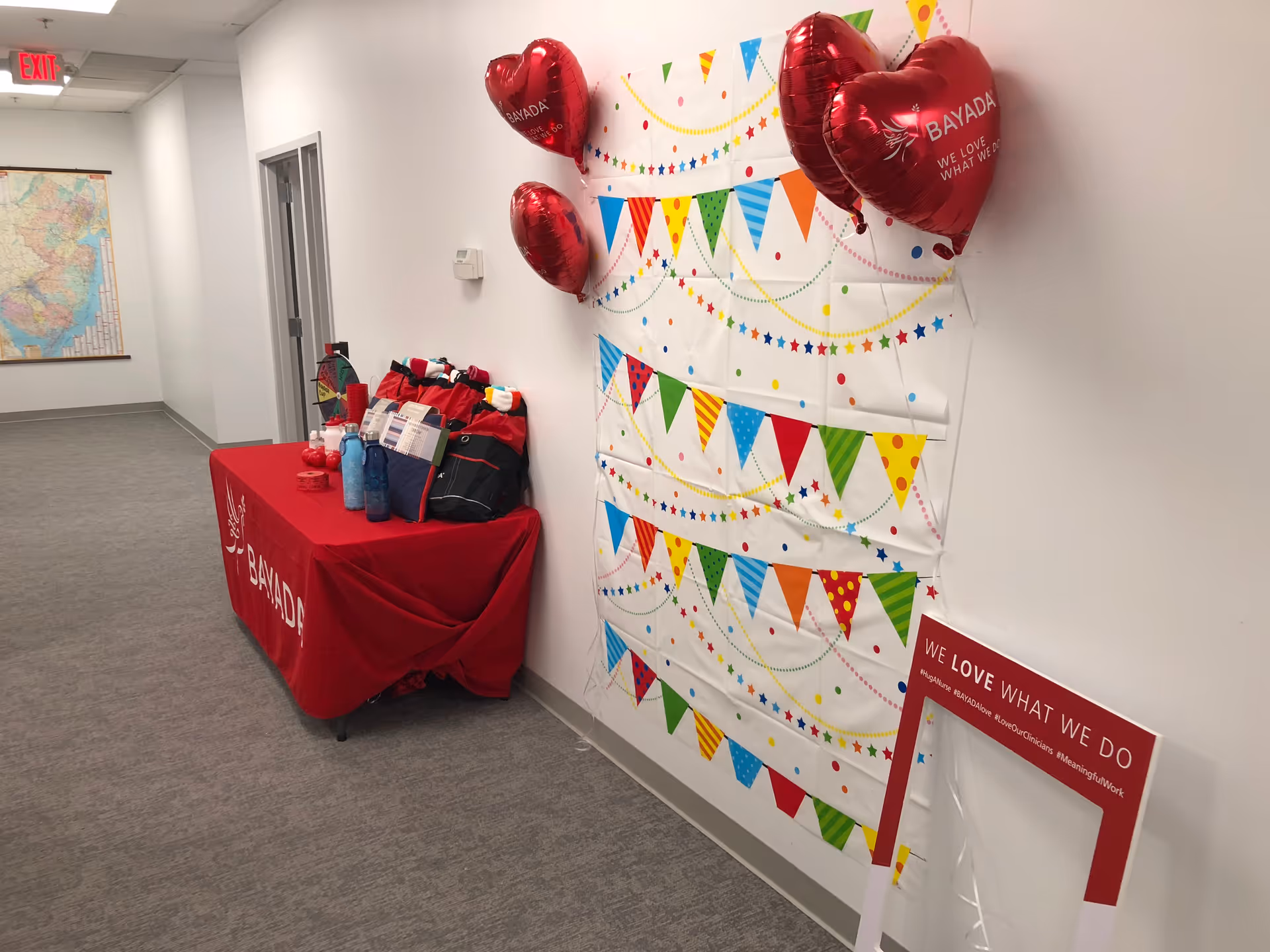 Hallway with a decorated BAYADA table, heart-shaped balloons, and colorful wall banners.