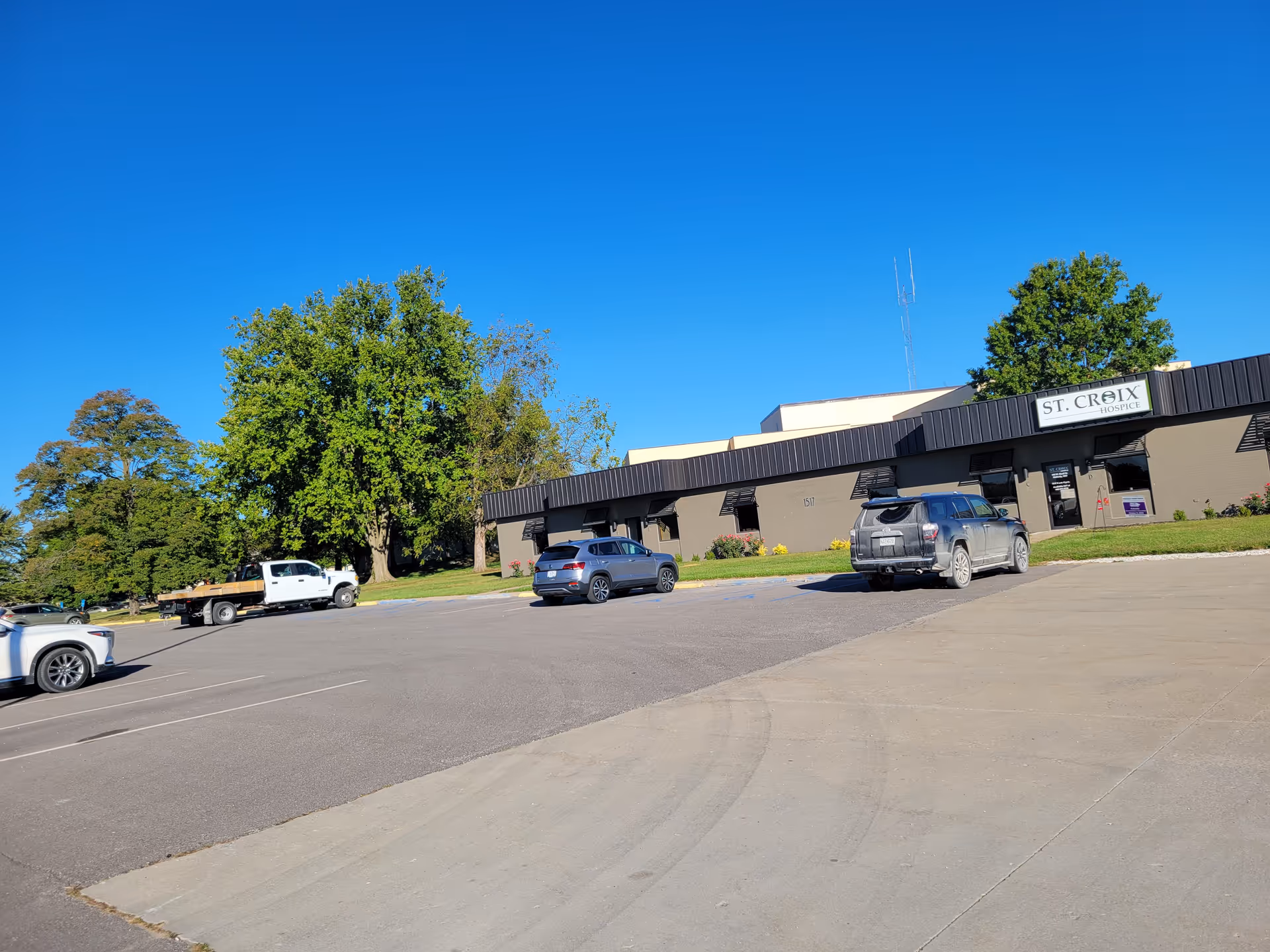 A single-story building with a St. Croix Hospice sign, parking lot, and blue sky.