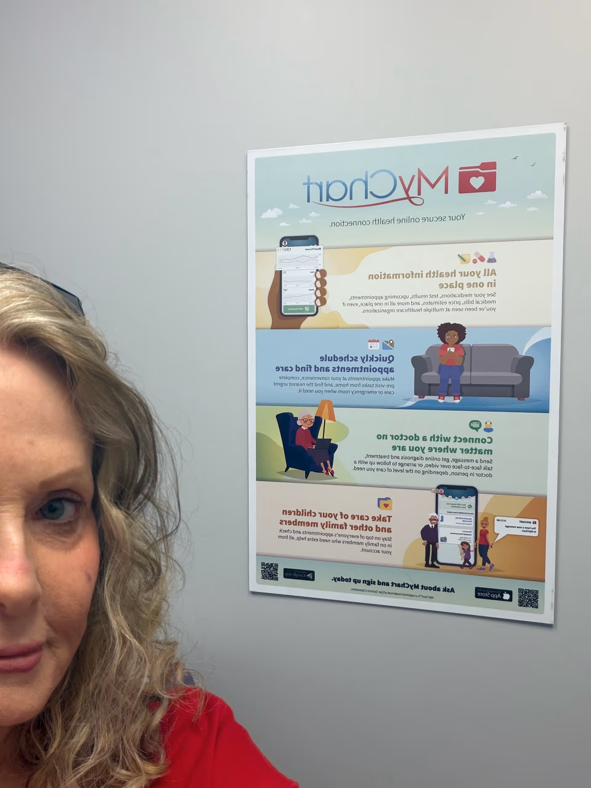Partial woman in red beside a colorful informational poster on the wall.
