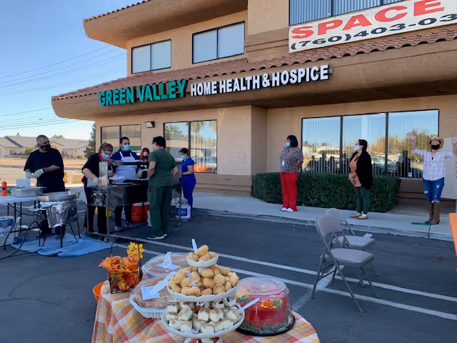 Outside Green Valley Home Health and Hospice, staff and residents gather for a barbecue near entrance.