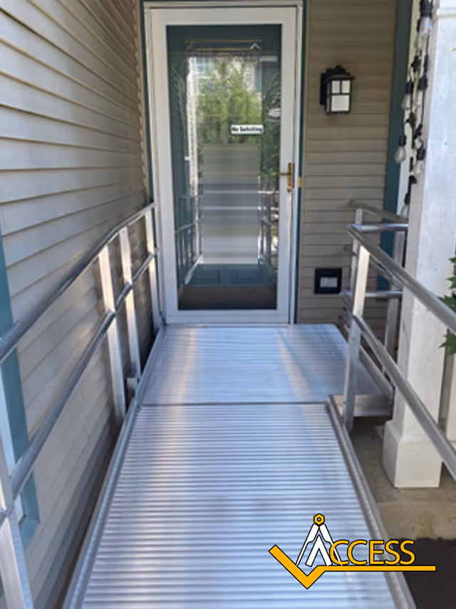 Metal ramp leading to a glass door entrance on a beige building.