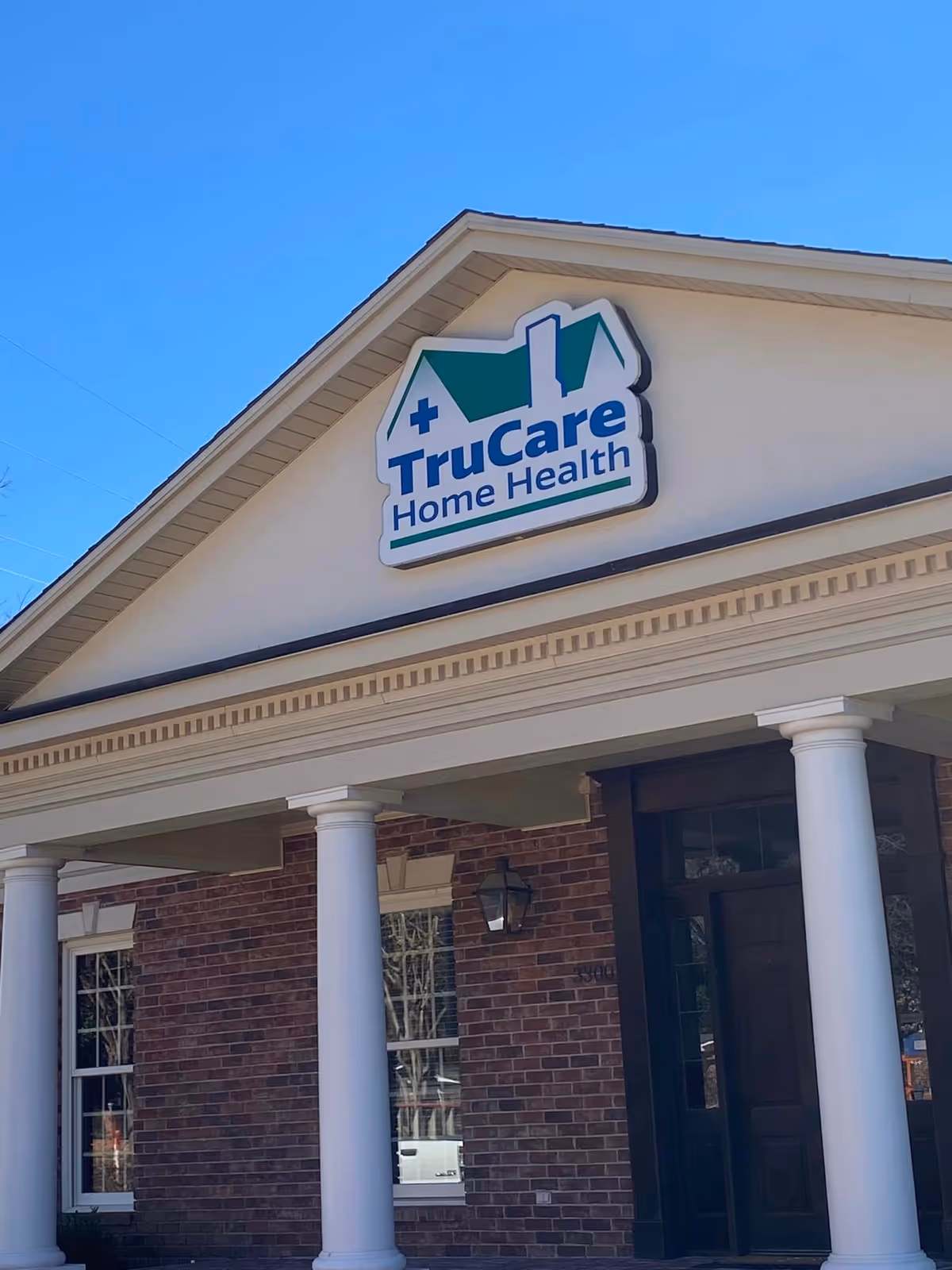 Exterior view of TruCare Home Health facility with sign and brick facade.