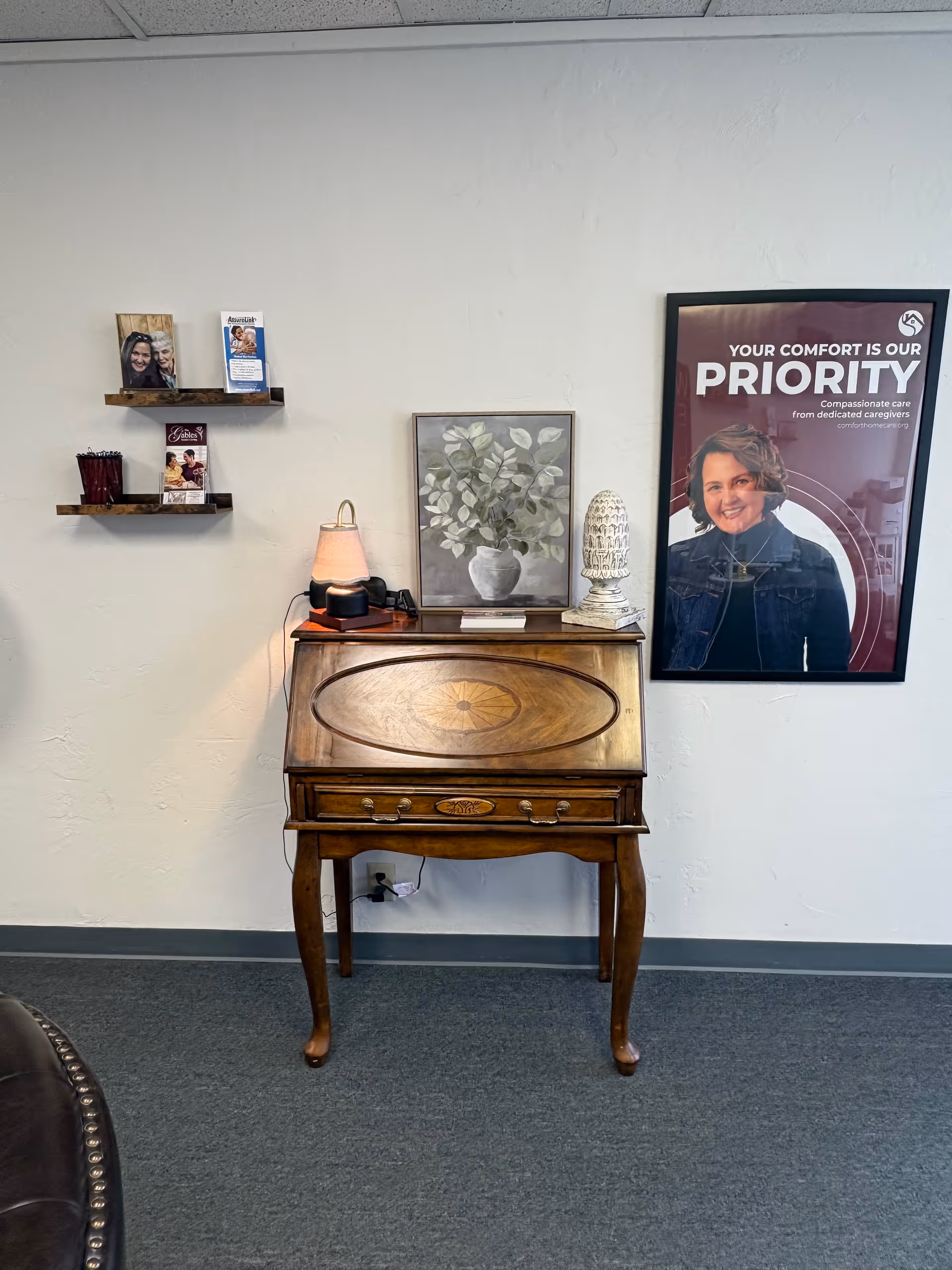 Antique wooden roll-top desk against a light wall with brochures and framed art.