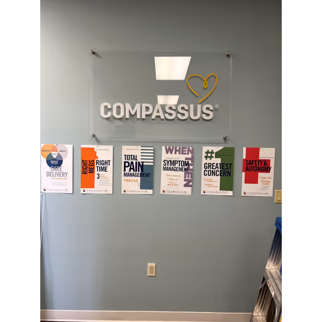 Interior wall with Compassus logo plaque and health-themed posters.