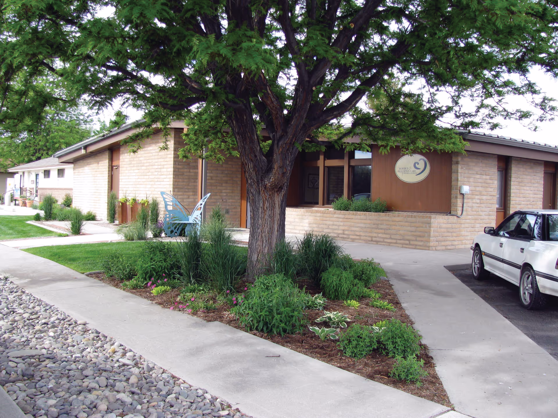 Exterior view of HopeWest Administrative Offices with landscaping and a parked car