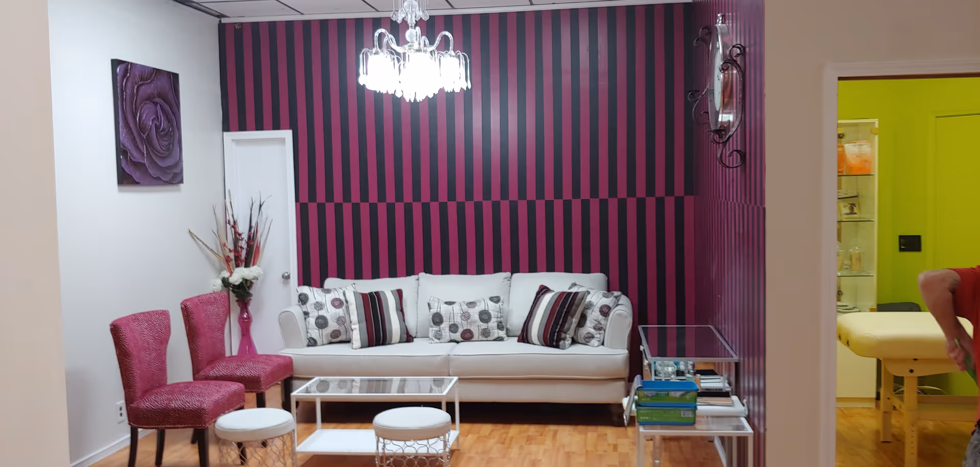 A modern lounge area with striped purple wall, white sofa, and pink chairs.