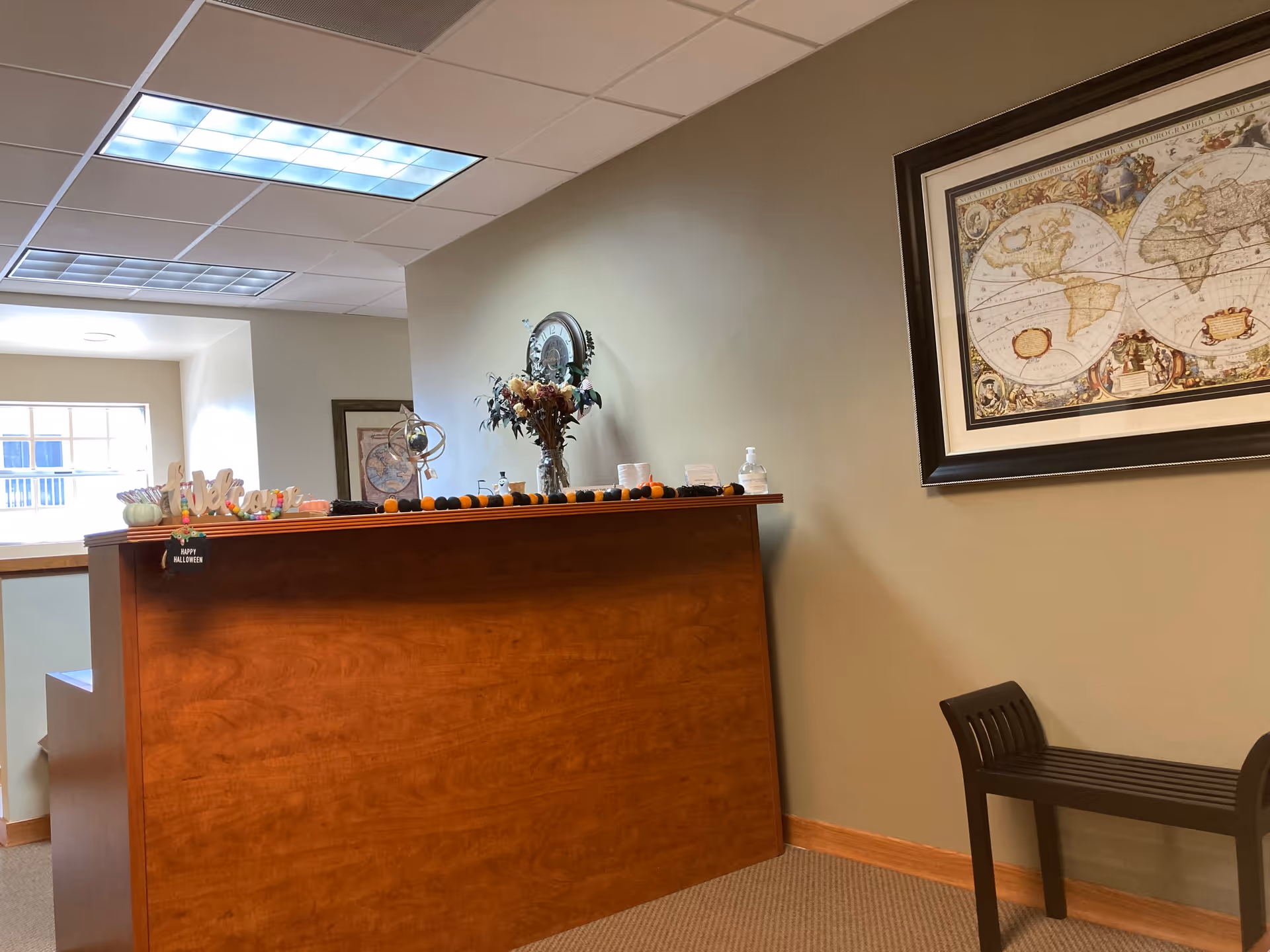 Wooden reception desk with flowers and a world map on the wall in a lobby.
