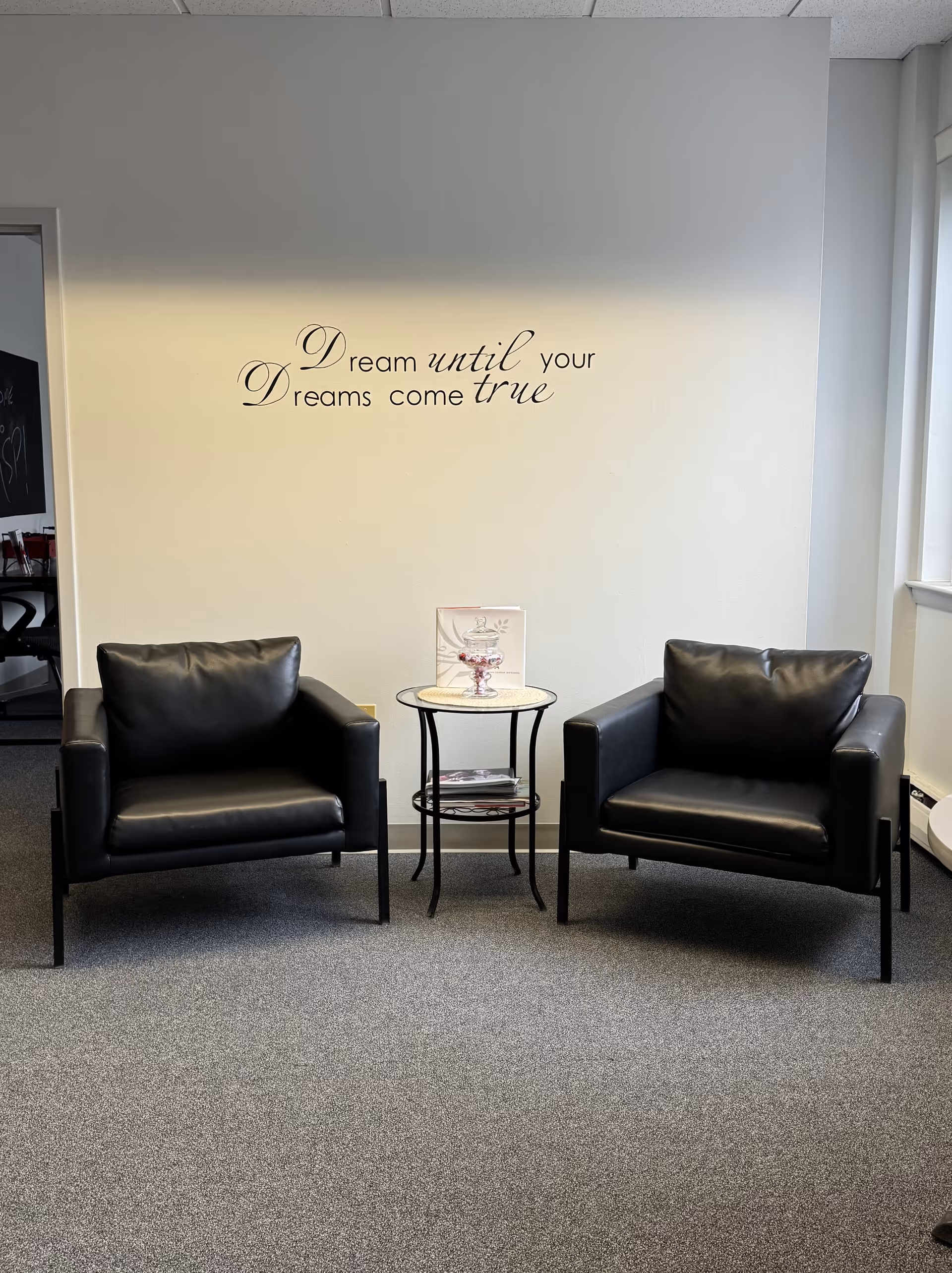 Two black armchairs flank a round table in a quiet lounge area.