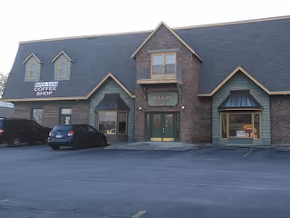 Exterior view of a brick building with storefronts and a parking lot