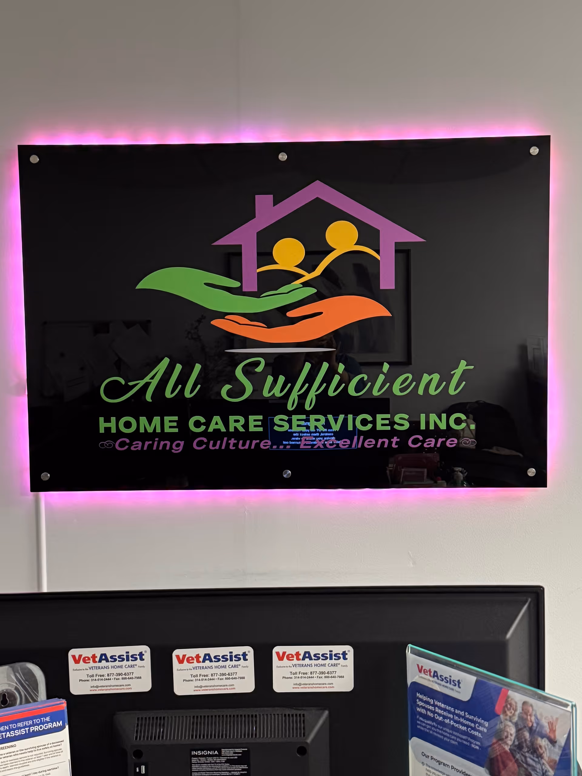 Interior reception area featuring a neon-lit sign for All Sufficient Home Care Services Inc.