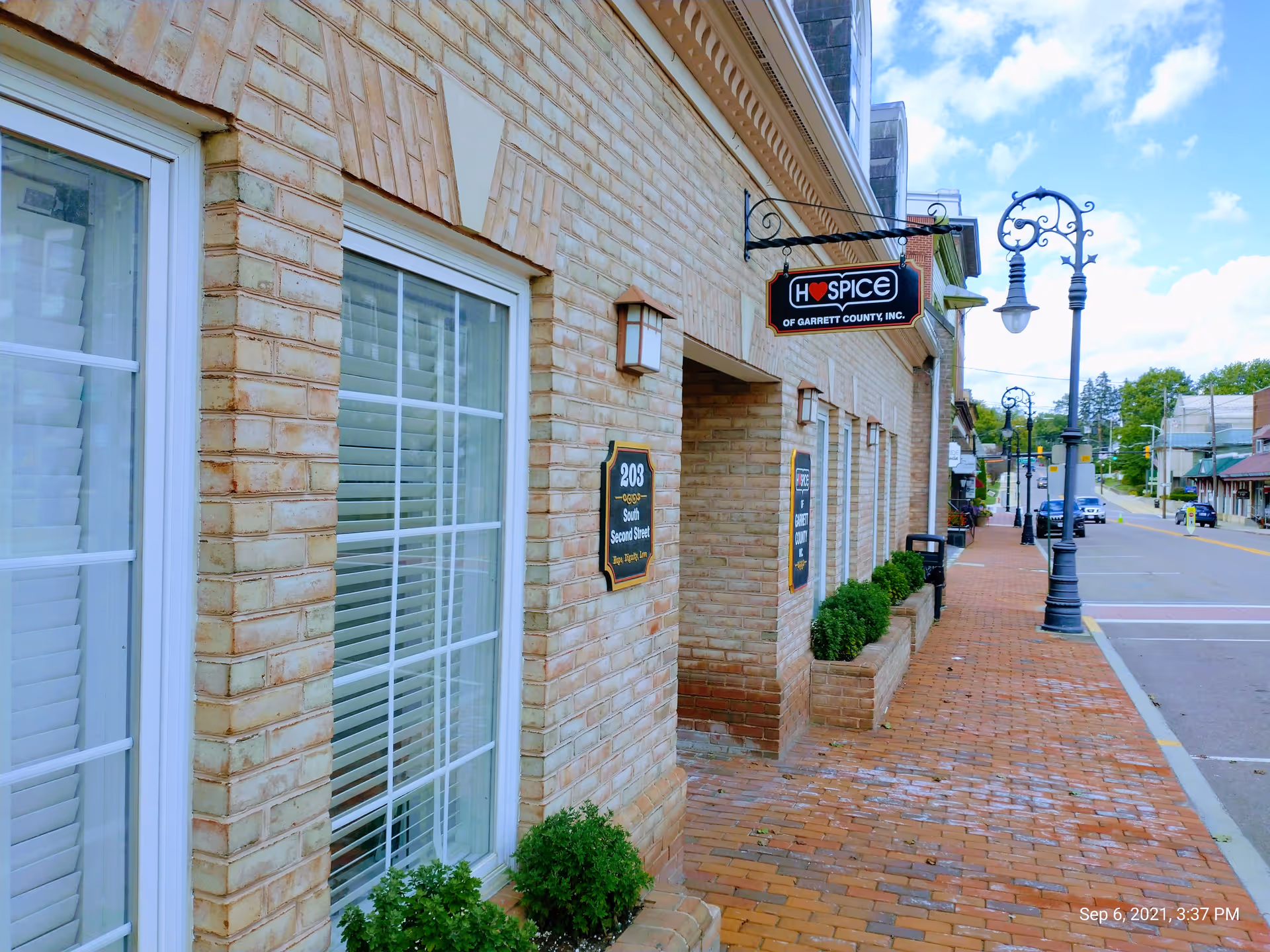 Brick building storefront along a brick sidewalk with Hospice of Garrett County sign.