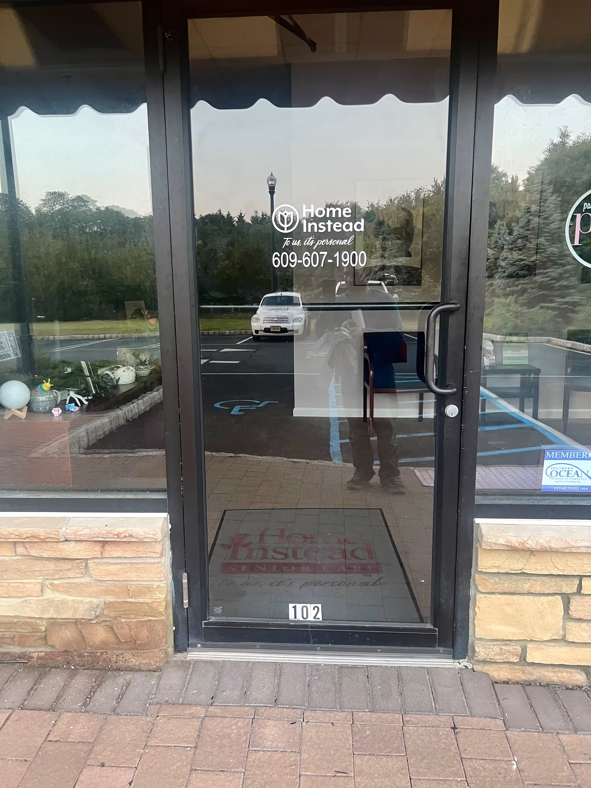 Glass storefront entrance of Home Instead with logo and phone number visible.