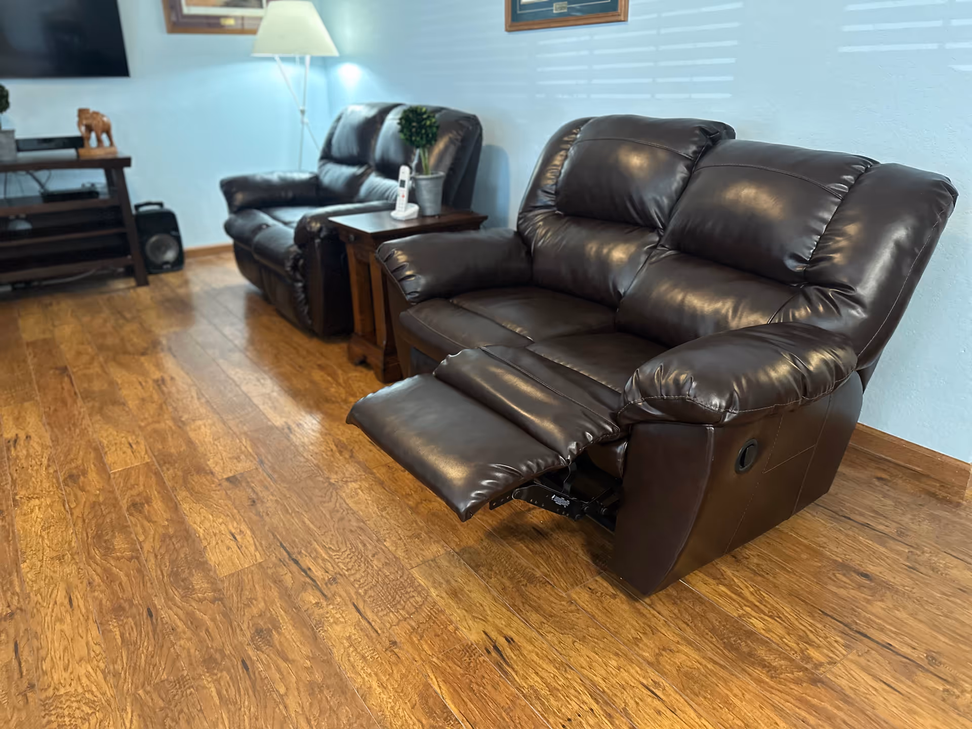 Brown leather recliners and a wooden end table sit in a cozy living room.