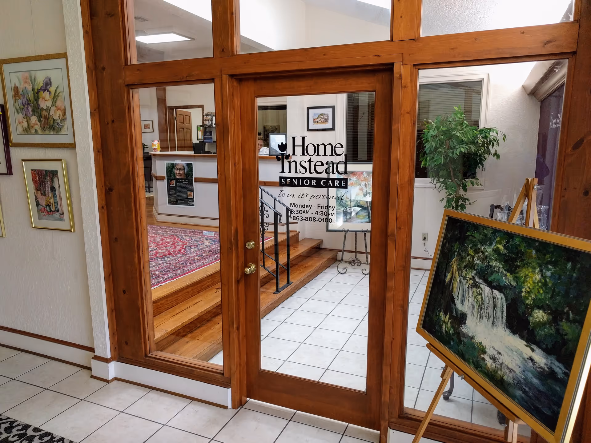 Wood-framed glass doors open to a lobby with a reception desk and Home Instead sign.