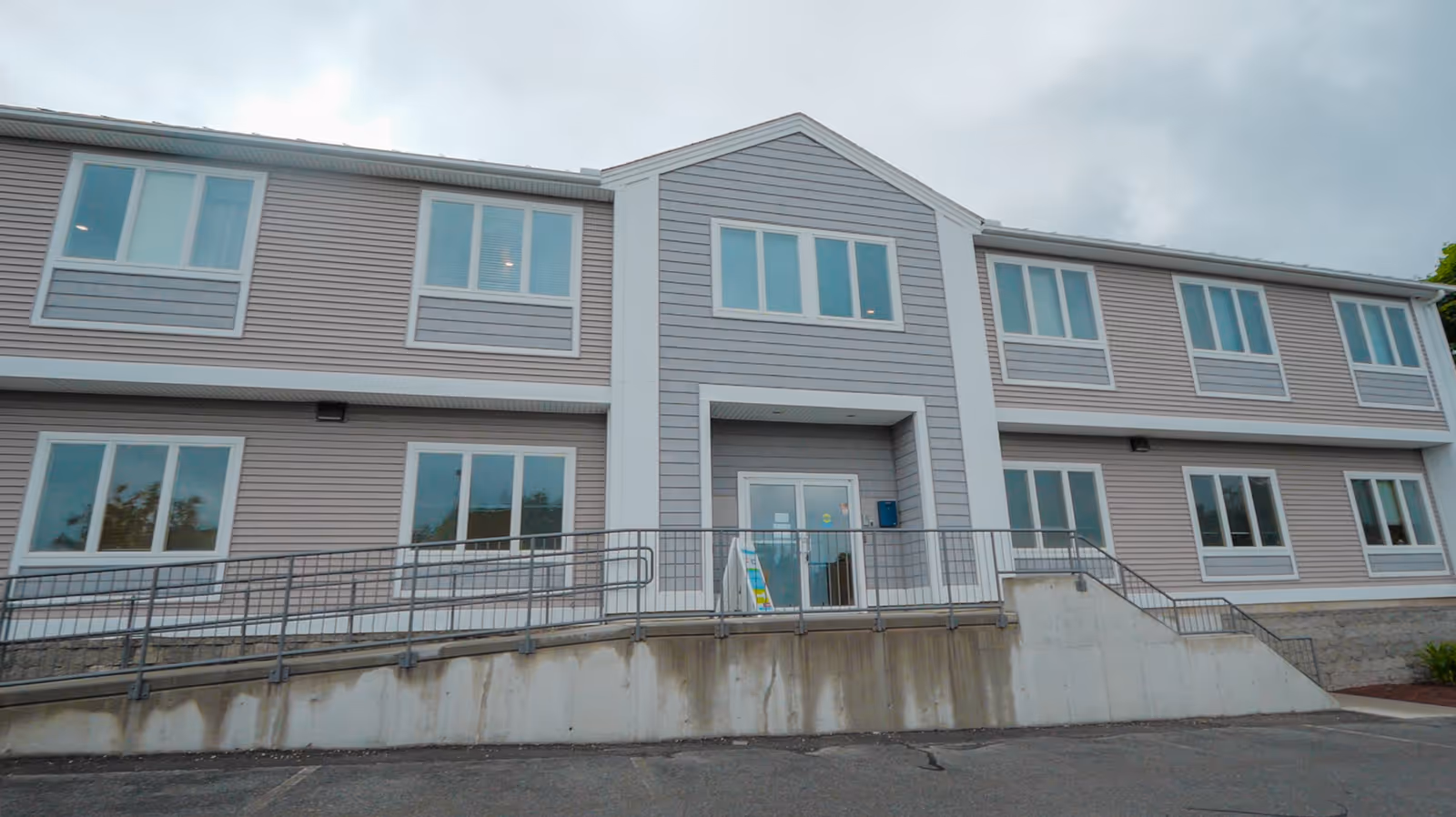 Front view of a two-story senior living facility with large windows and a ramp.