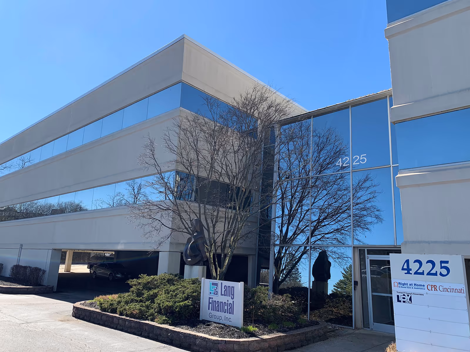 Modern office building with blue glass, leafless trees, and Right at Home signage at 4225