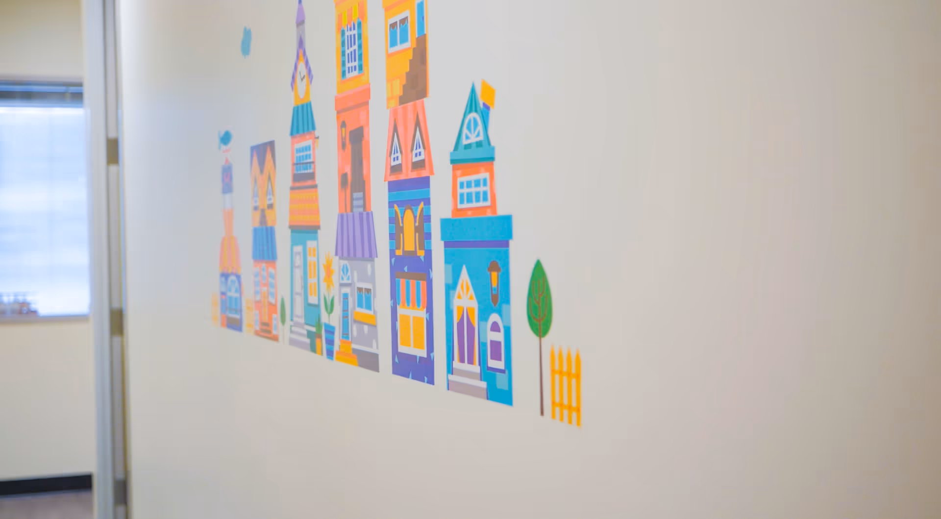Colorful cartoon houses mural on a white interior wall inside the facility.