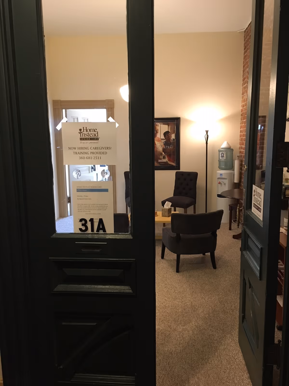 Entrance to a waiting area with chairs, a water cooler, and a sign on the door.