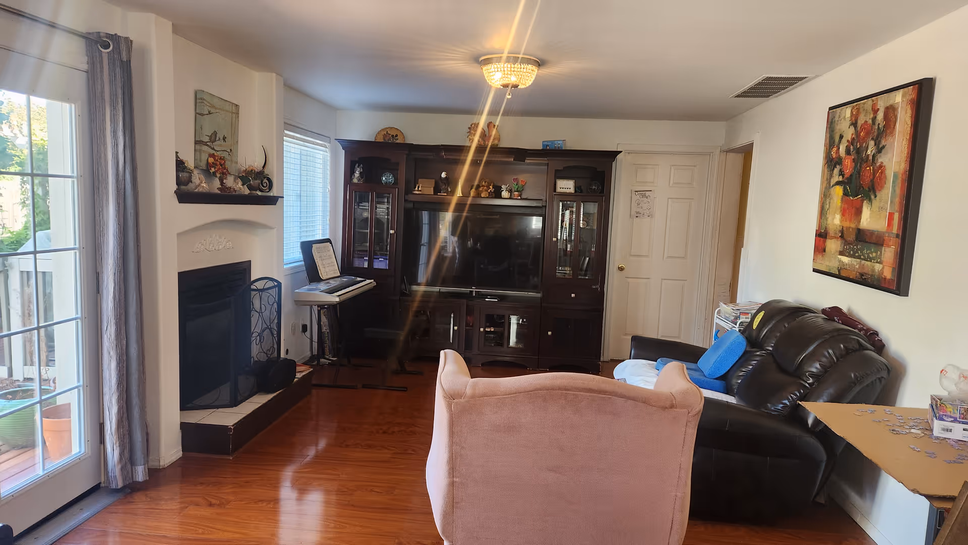 Cozy living room with leather sofa, pink chair, entertainment center, and fireplace.