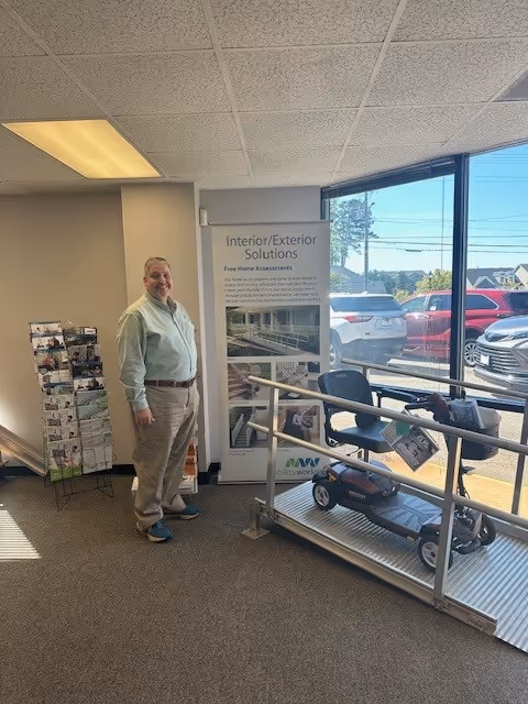 A man stands inside a MobilityWorks showroom beside a mobility scooter display.