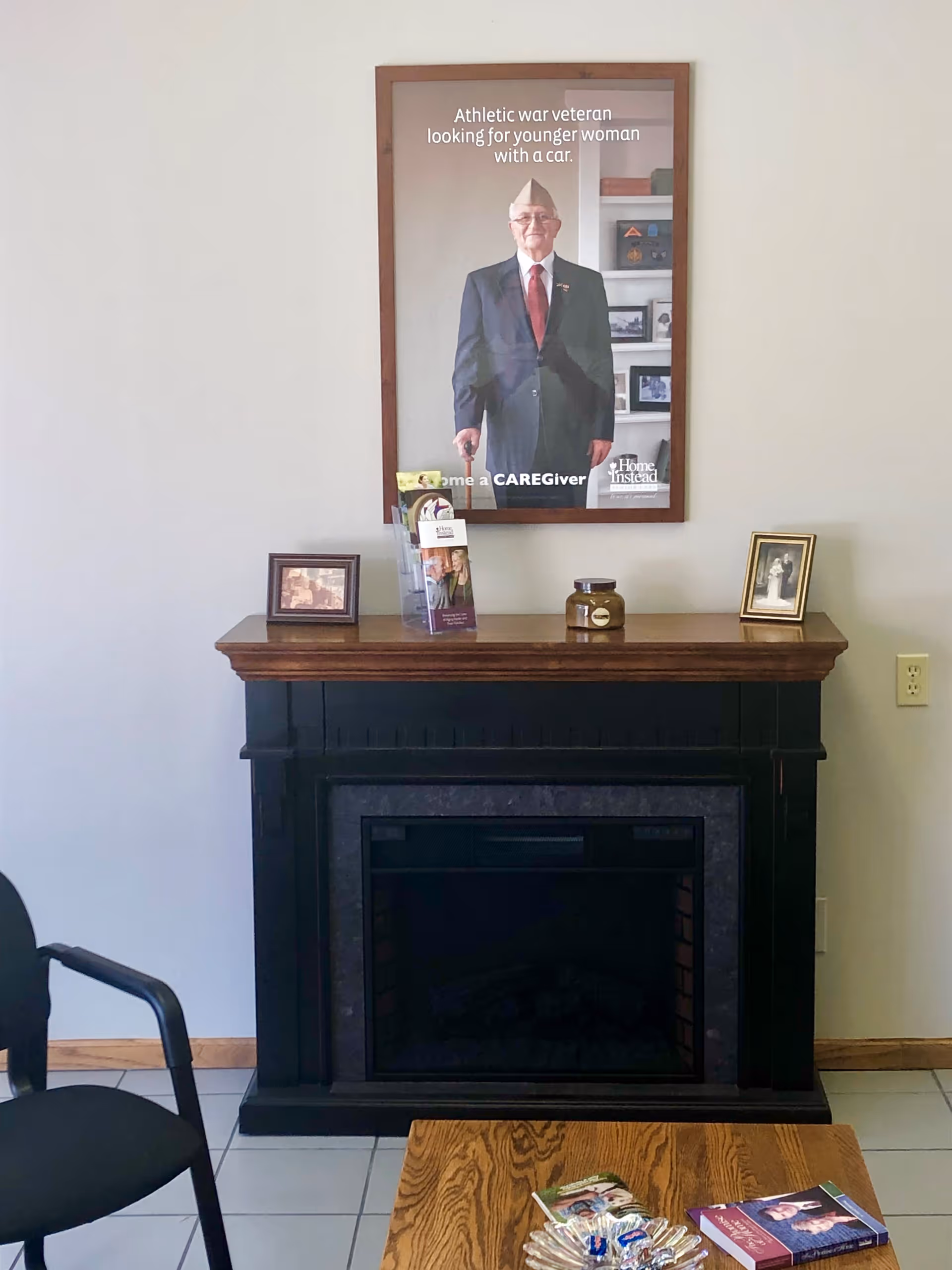 Framed poster above a dark fireplace mantel with small photos and decor.