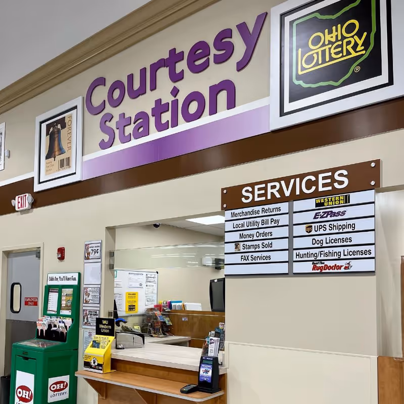 Interior of a Discount Drug Mart courtesy station with a service counter and signage.