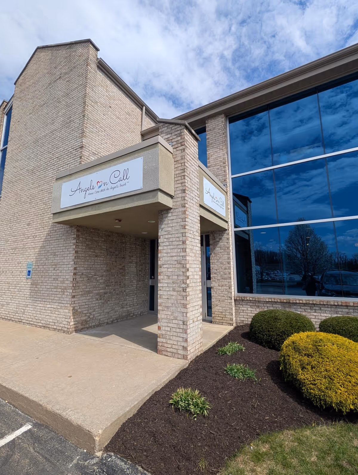 Brick building entrance with Angels On Call sign and large glass windows.