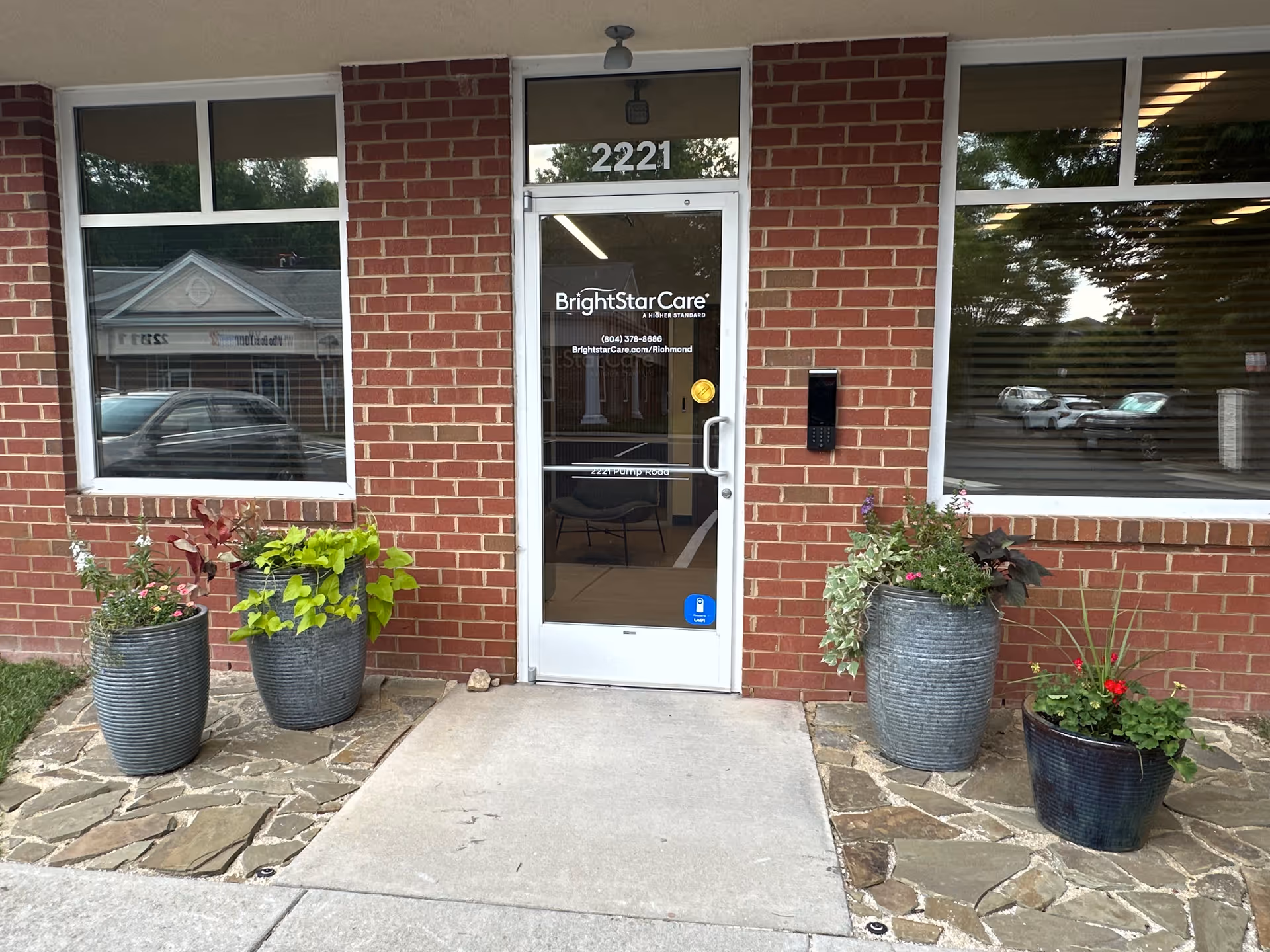 Brick exterior entrance with glass door labeled BrightStarCare and potted plants outside.